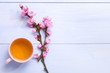 Cup of green tea and  branches of blossoming peach on lilac wooden table