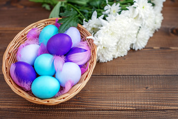 Wall Mural - Flowers and eggs in a basket on a wooden background. Concept Happy Easter.