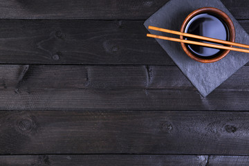 Wall Mural - Sushi chopsticks and soy sauce on black background. Top view with copy space.