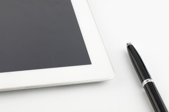 Tablet computer and a modern metal black-silver pen on a white background