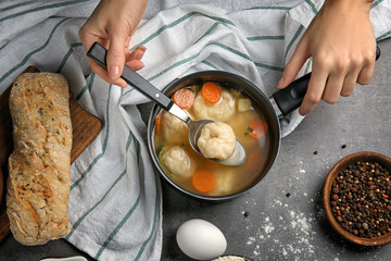 Wall Mural - Female hands holding stewpan with delicious chicken and dumplings on kitchen table