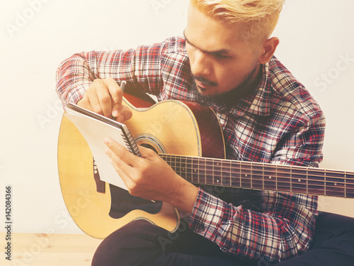 Fotografía Young hipster composing the song with guitar .