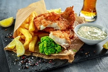 British Traditional Fish And Chips With Mashed Peas, Tartar Sauce On Crumpled Paper With Cold Beer.