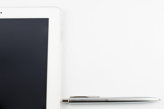 Tablet computer and a modern metal silver pen on a white background copy space