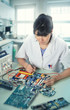© tilialucida - Young female tech or engineer repairs electronic equipment in research facility