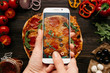 © fedorovacz - Photographing food. Hands taking picture of delisious pizza with smartphone
