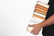 © JuanCi Studio - Young man holding a pile of books against a white wall. Empty copy space for Editor's text.