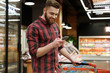 © Drobot Dean - Cheerful young man in supermarket with shopping trolley
