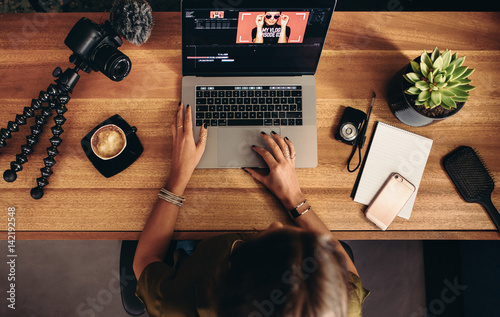 Fotomural Young female vlogger editing her vlog on computer.