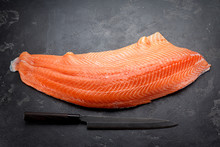 Fresh Raw Salmon Fillet With Chef Knife Over Dark Stone Background