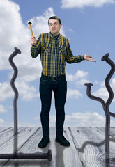 Wall Mural - Funny young man with hammer and giant metal nails