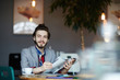 © pressmaster - Young man with journal sitting in cafe at coffee-break