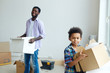 © pressmaster - Boy holding box with house supplies while helping his father at home