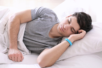 Wall Mural - Young man with sleep tracker resting in bed at home