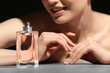 © Africa Studio - Beautiful young woman with bottle of perfume on dark background, closeup