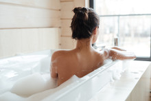 Young Woman Having Bubble Bath And Looking At Window