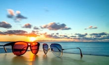 Vacations Concept With Sunglasses On Tropical Beach Table At Sunset