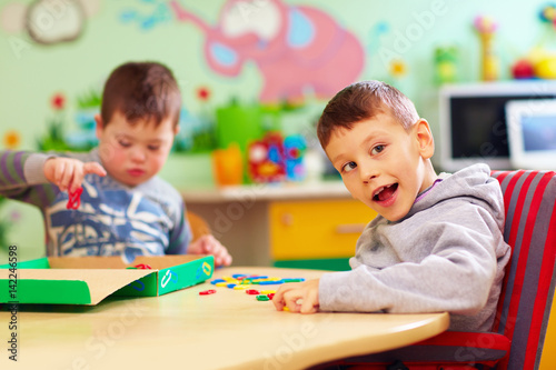 Fotografía cute kids with special needs playing with developing toys while sitting at the d