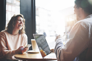 Beautiful, happy and young couple talking and working on laptop. Flare effect