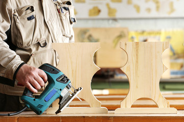 Woodworker with electric jigsaw in carpentry