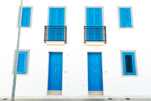 The White Wall With Blue Doors And Windows Of The Typical House In San Vito Lo Capo, Italy