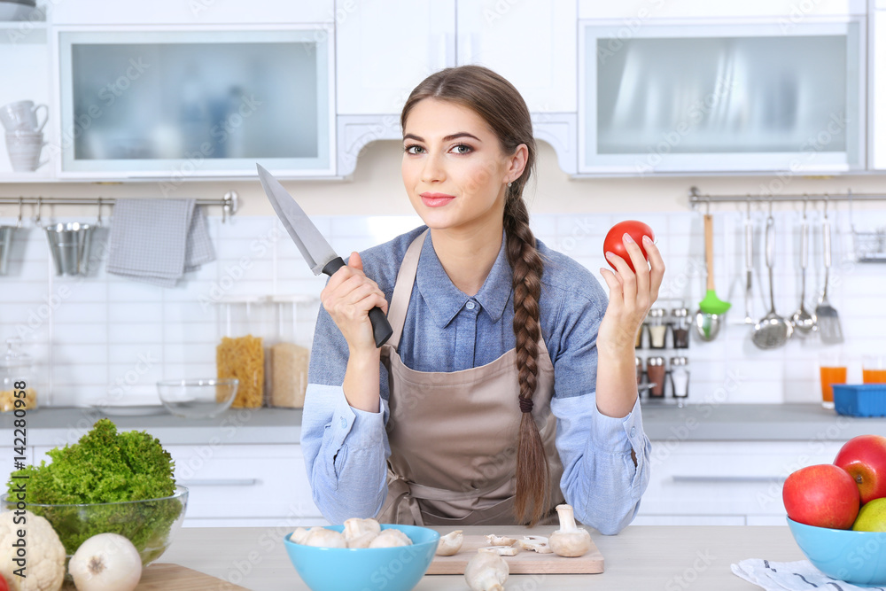 Cooking concept. Young woman with knife on kitchen
