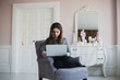 © romankosolapov - Young woman at home in the armchair relaxing in her lliving room with laptop