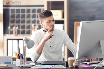 Canvas Print - Young male designer working in office