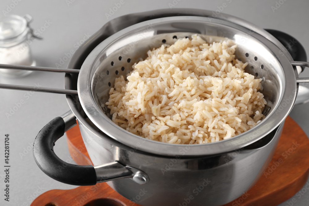 Colander with prepared rice in saucepan