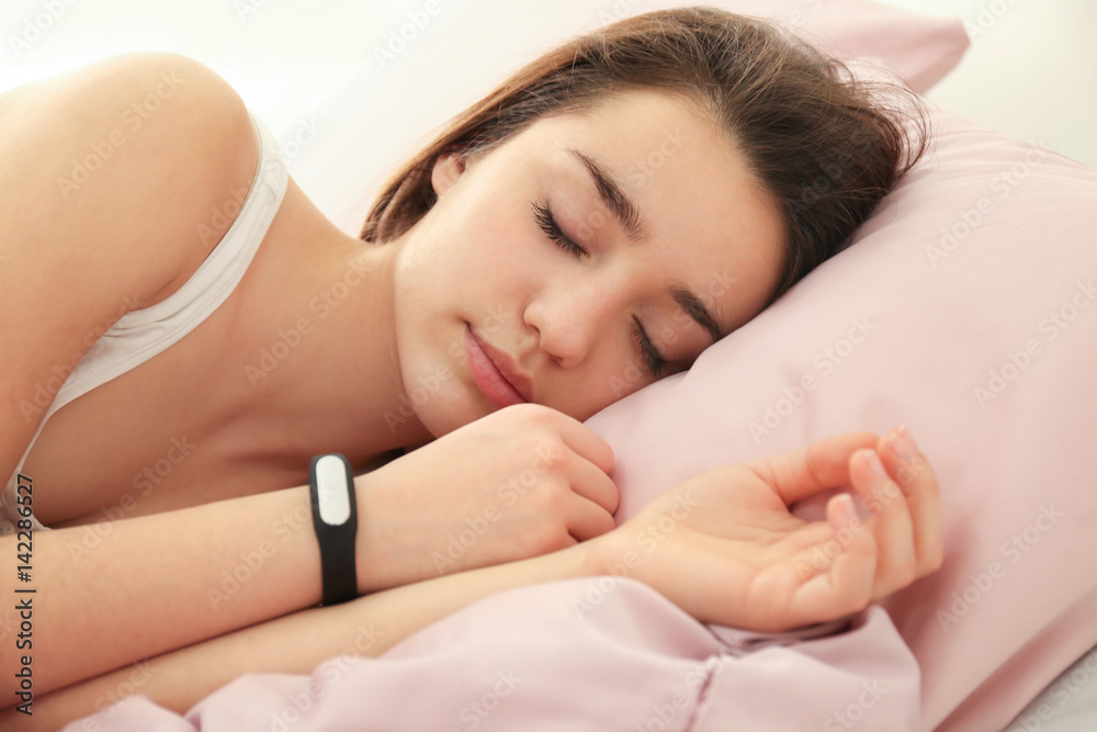 Young woman with sleep tracker resting in bed at home