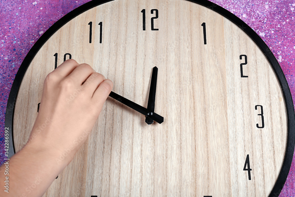 Female hand change time on big wall clock