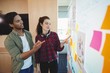© WavebreakMediaMicro - Male and female graphic designers discussing over sticky notes