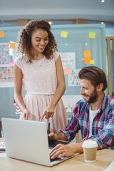 Wall Mural - Graphic designers interacting while using laptop 