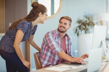 Wall Mural - Graphic designers interacting while working on personal computer