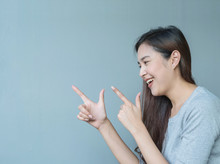 Closeup Asian Woman Holds Up One Finger In Two Hand Point To Space With Smile Face Emotion On Blurred Cement Wall Textured Background With Copy Space
