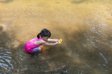 Wall Mural - Asian Chinese little girl playing toy boat in the creek