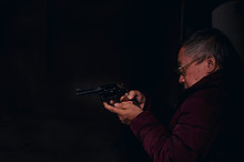 Dangerous Old Man Pointing A Gun At The Target On Dark Background, Selective Focus On Gun, Dark Tone,Crime Concept
