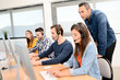© W PRODUCTION - group of young people with desktop computer in row and headset training with teacher instructor in customer service call support helpline business center