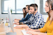 © W PRODUCTION - group of young people telephone operator with headset working on desktop computer in row in customer service call support helpline business center