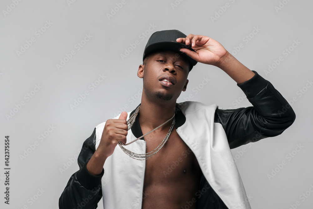 Young african american gangster man portrait on grey background with free space. Neglecting, arrogance, swagger, self-assumption. Ghetto, challenge to society, cheeky, cool, rebellious