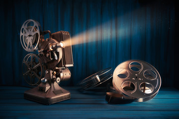 vintage 8mm movie projector with 35mm reels and film on a wooden background with dramatic lighting