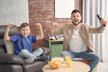 Wall Mural - Father and son watching football on TV at home