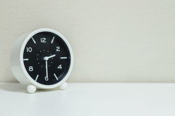 Closeup black and white alarm clock for decorate show show half past two o'clock or 2:30 p.m. on white wood desk and cream wallpaper textured background with copy space