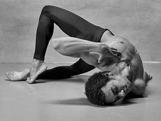 The male ballet dancer posing over gray background