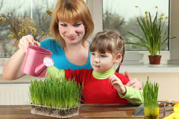 Mom and daughter watering a green onion