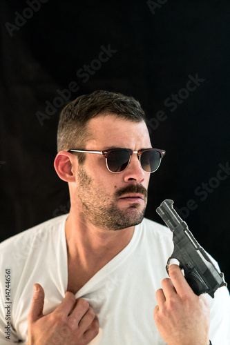 Young man with eyeglasses looking scared at his handgun Poster