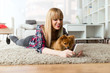 © nenetus - Beautiful young woman with her dog using mobile phone at home.