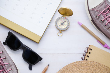 Traveler accessories and compass on white wooden background. View from above with blank notebook.