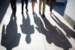 © pressmaster - Two businesswomen and three businessmen walking along street, their shadows reflecting on shabby asphalt