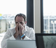 © Westend61 - Exhausted businessman sitting at desk in office